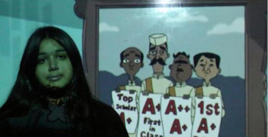 Junior Mishal Charania stands in front of a scene from Phineas and Ferb. In this episode, Baljeet, the only Indian character on the show, sang about the importance of getting good grades in his life. 