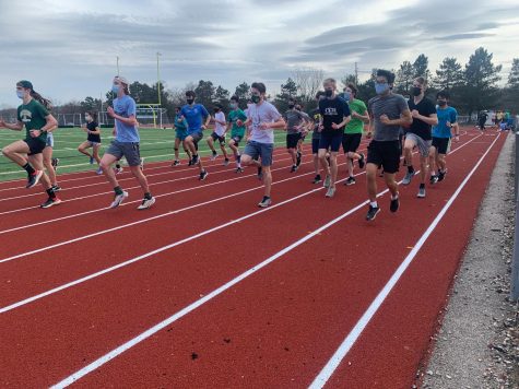 On the opening day of spring sports, track athletes warm up for practice.