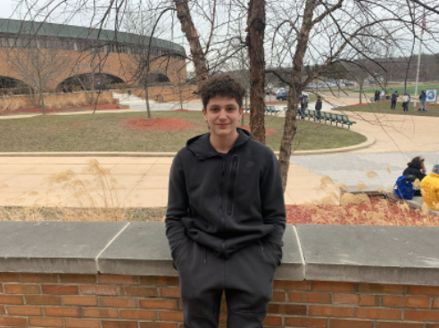 Kyce Shamma sitting on a ledge outside the Huron cafeteria during his lunch period.