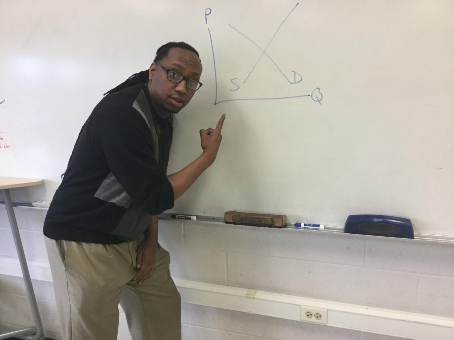 Tucker poses in front of a supply and demand graph in his economics classroom.