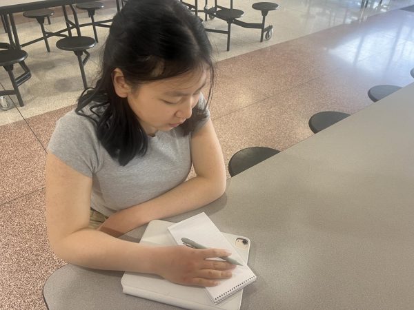 Jamie Tang writes notes to cover the school board updates at Huron High School. 
