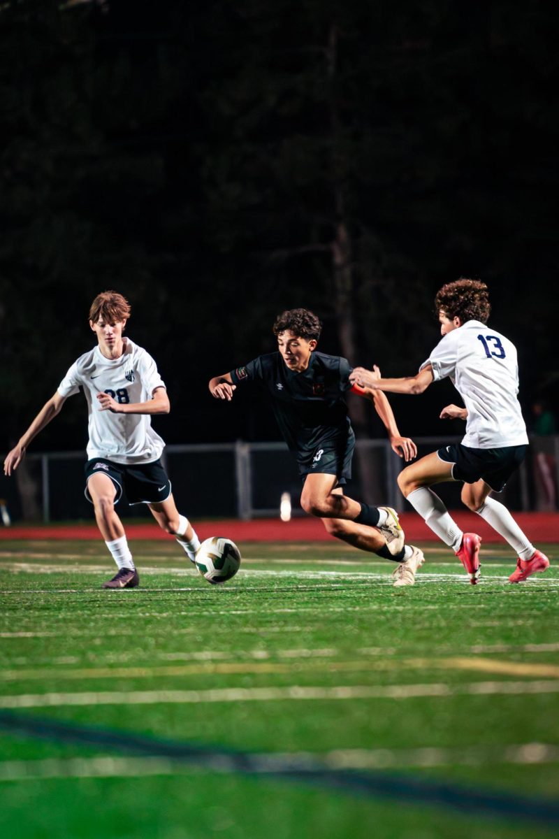 Leucht dribbles past two Pioneer defenders while searching for a passing option. 