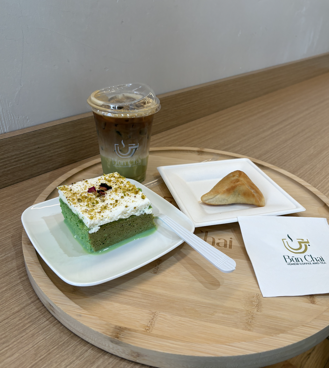 Pistachio latte, pistachio milk cake, and spinach pie on the serving platter at Bun Chai.