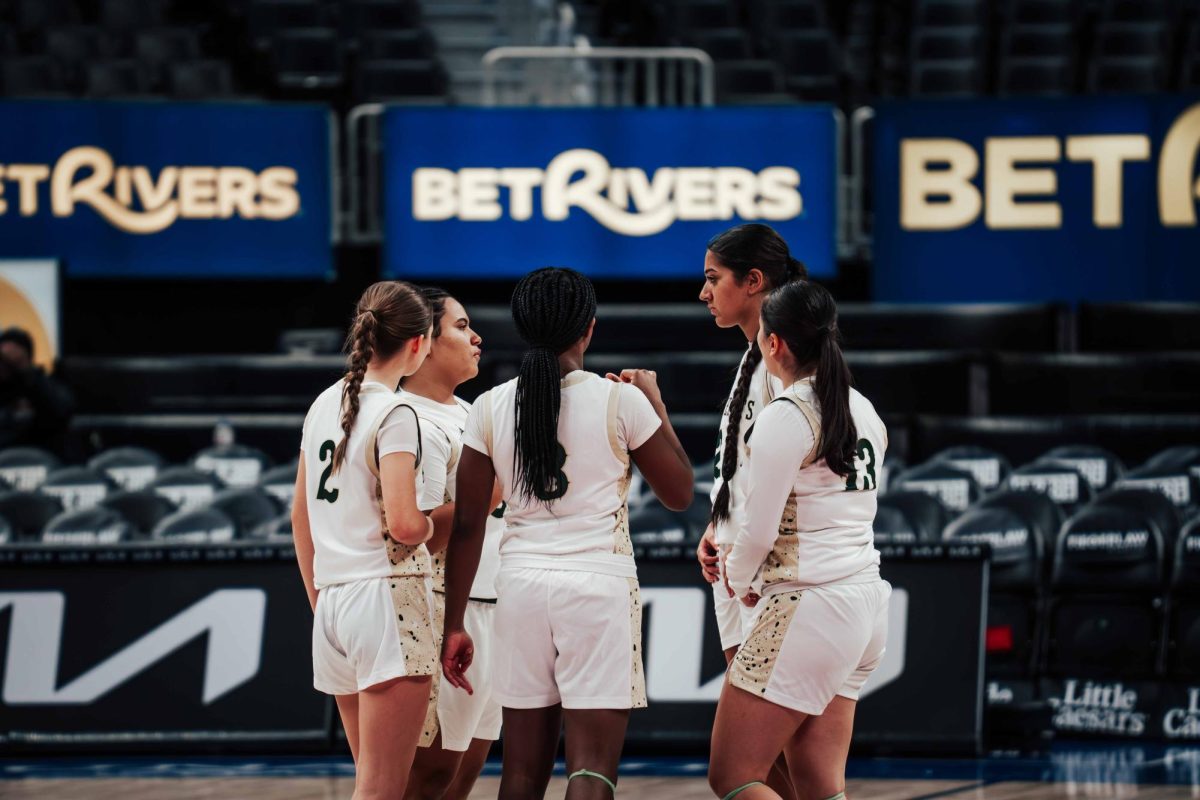 Junior Charlotte Wright, senior Alia Anthony, sophomore Chloe Frierson, junior Maddie Lyu, and sophomore Sansita Sachin (left to right) huddle together at Little Caesars Arena to discuss the plan for the upcoming quarter.