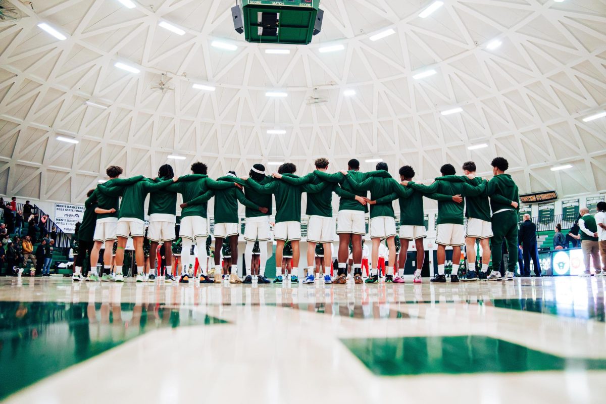 The Huron men's varsity basketball team stands together during the national anthem before their last game of the regular season on Feb. 19.