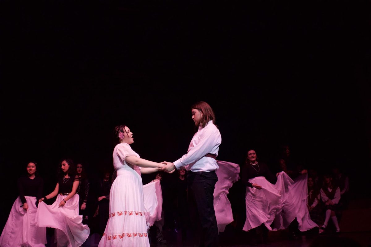 Huron seniors Violet Diem and Fynn Murphy hold hands center stage during “Talia."
