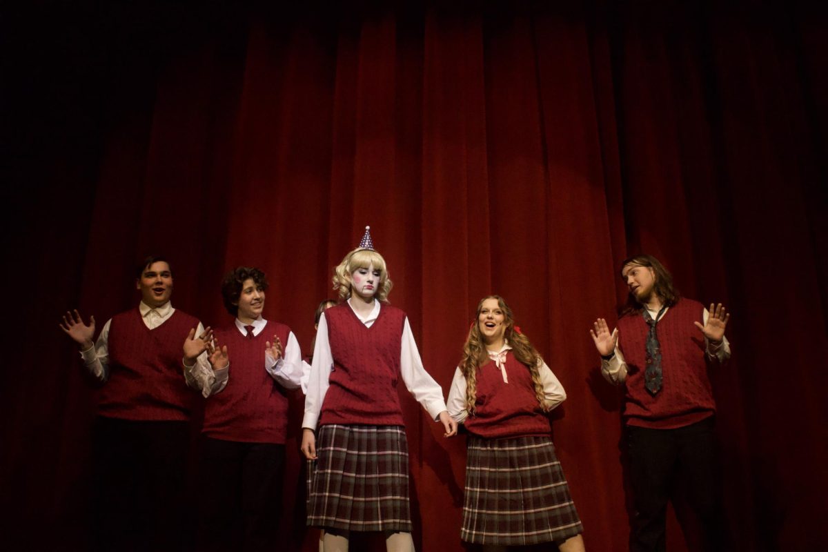 Pioneer freshman Elisabeth Gaylor (Jane Doe) stands center stage under the lights, capturing the eerie presence of Jane Doe as the cast lingers in the background.
