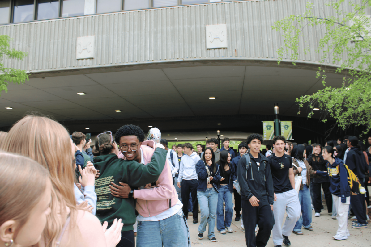 Senior Mamoud Kaba walks through the arch and gives teacher Sara-Beth Badalamente a hug.