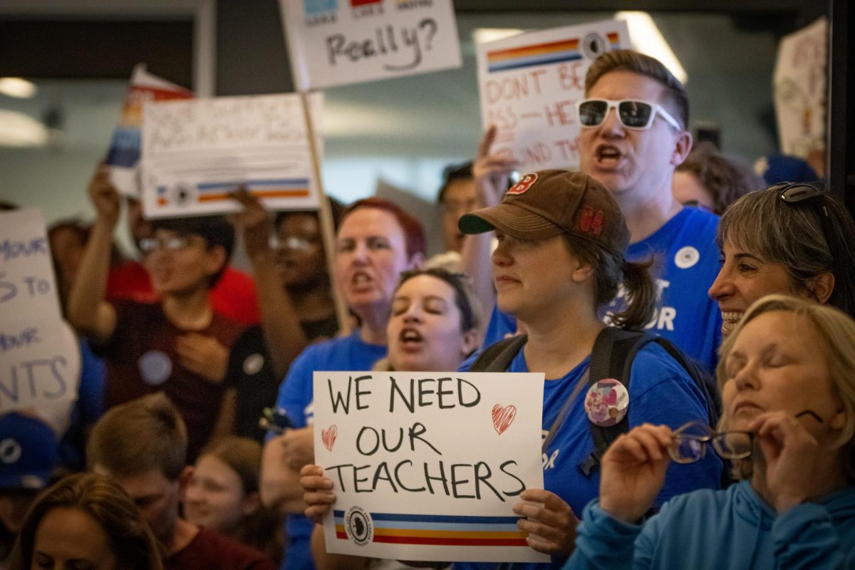 The AAPS community chants and holds up signs within the Earhart building before the beginning of the board meeting.